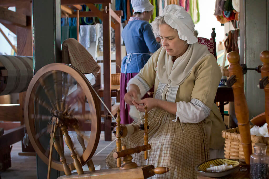 Colonial woman at spinning wheel